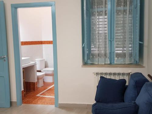 a living room with a blue couch and a bathroom at CASA CASCIOTTO in Palermo
