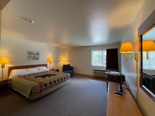a hotel room with a bed and a flat screen tv at Ausable Valley Inn in Mio