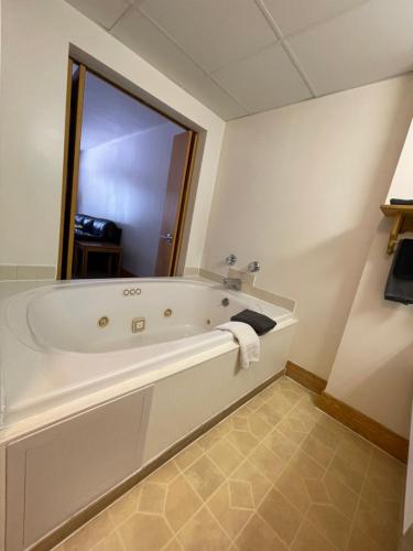 y baño con bañera y espejo. en Ausable Valley Inn, en Mio
