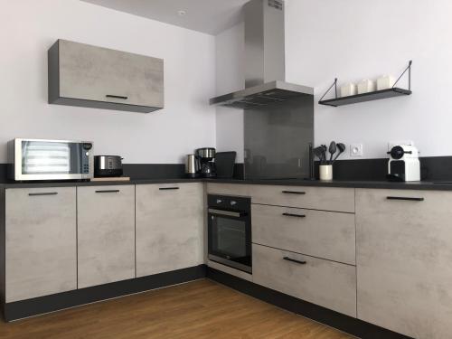 une cuisine avec des placards en acier inoxydable et un four micro-ondes dans l'établissement Ty Albertine - Maison de campagne rénovée proche de la mer, à Plonévez-Porzay