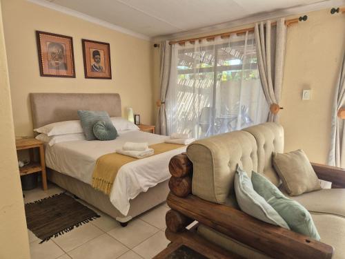 a bedroom with a bed and a couch and a window at KatiKati Eco Lodge in White River