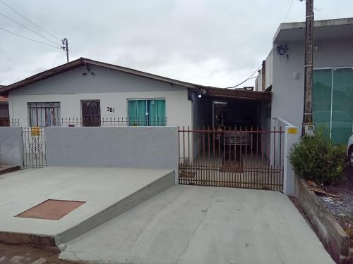 Uma casa branca com um portão à frente. em POUSADA ALTERNATIVA MANU LAGES suite em Lages
