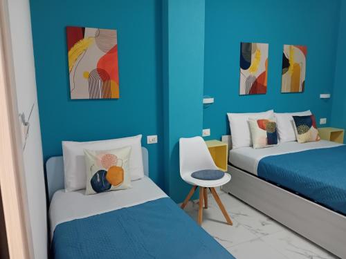 a blue room with two beds and a chair at KeyRooms in La Spezia