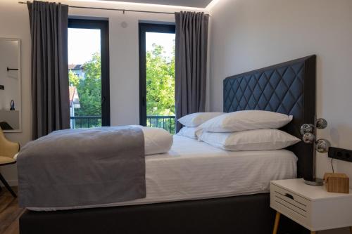 Schlafzimmer mit einem Bett mit blauem Kopfteil und Fenstern in der Unterkunft Villa of Senses in Bihać