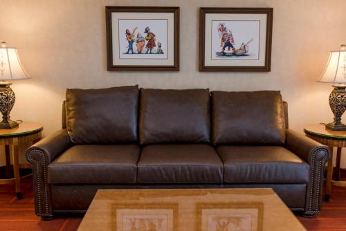 a brown leather couch in a living room with two lamps at Howard Johnson by Wyndham Anaheim Hotel & Water Playground in Anaheim