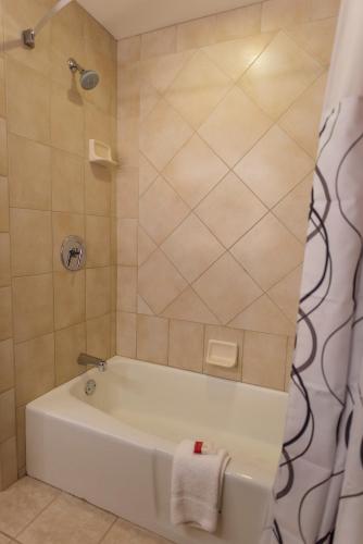 a bathroom with a white tub and a shower at Howard Johnson by Wyndham Anaheim Hotel & Water Playground in Anaheim