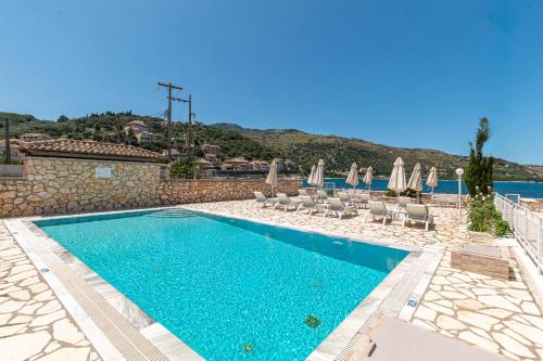 a swimming pool with chairs and umbrellas at Serenity House Kassiopi in Kassiopi
