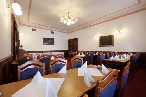 a dining room with tables and chairs and a chandelier at Hotel U Černého orla in Telč