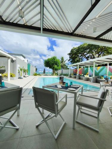 an outdoor patio with a table and chairs next to a swimming pool at Apartment in a Tropical Oasis, Ki Residences, Pereybere - Managed by KSN in Pereybere