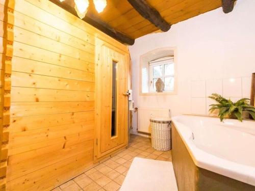 ein Badezimmer mit einer Badewanne und einer Holzwand in der Unterkunft Attractive apartment in Katzweiler in Brakel