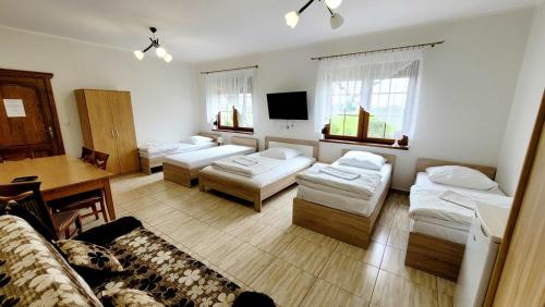 um quarto com quatro camas, uma mesa e janelas em Gościniec Krys em Znin