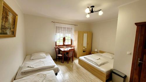a room with two beds and a table with a window at Gościniec Krys in Żnin