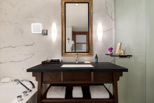 a bathroom with a sink and a mirror and a tub at Hyatt Vancouver Downtown Alberni in Vancouver