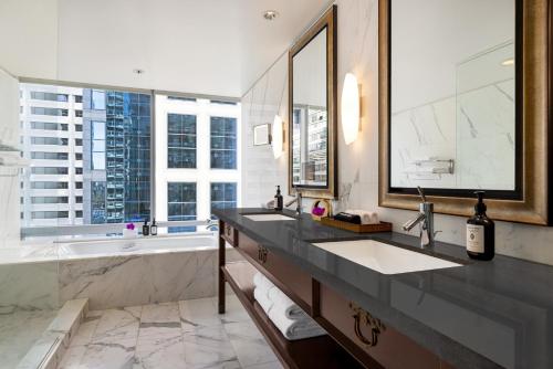 a bathroom with two sinks and a tub and a large mirror at Hyatt Vancouver Downtown Alberni in Vancouver