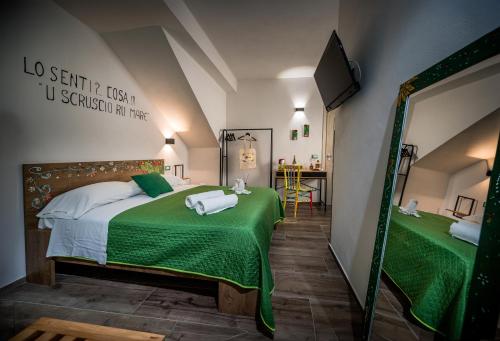 a bedroom with a bed with green sheets and a mirror at Kalifè Vacanze in Castellammare del Golfo