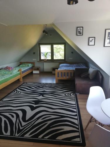 a attic room with two beds and a zebra rug at Agroturystyka Cisza Knyszyńska in Wólka