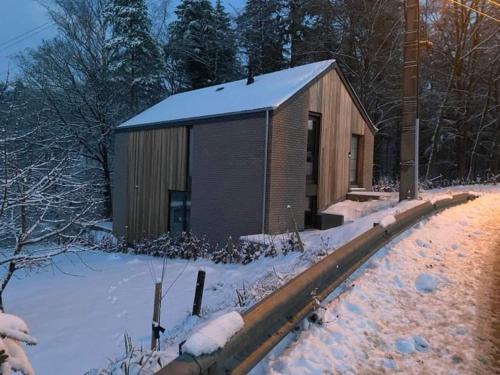 a small building with snow on the ground next to a curb at Gîte de la Tour in Hotton
