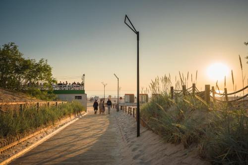 two people walking down a path on the beach at Liepājā 4:10 pm in Liepāja