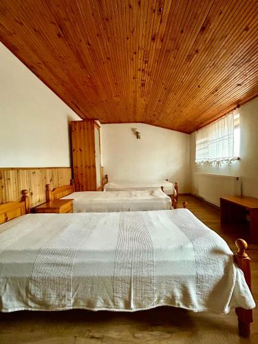 ein großes Schlafzimmer mit zwei Betten und einer Holzdecke in der Unterkunft Torlacite in Chiprovtsi