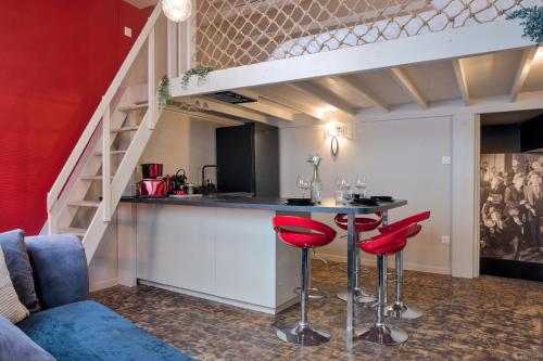 une cuisine loft avec un bar et des tabourets rouges dans l'établissement UnSejourAMetz - Le cinéma de Marilyn, à Metz