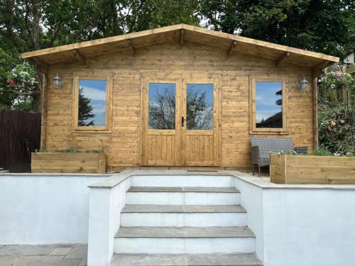 a wooden shed with a set of stairs in front at Estuary View Cabin in Penclawdd
