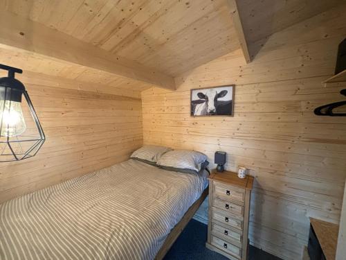 a bedroom with a bed in a wooden cabin at Estuary View Cabin in Penclawdd