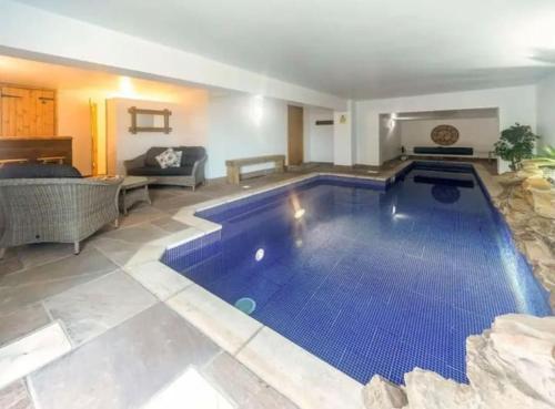 a large blue swimming pool in a living room with a couch at Estuary View Cabin in Penclawdd