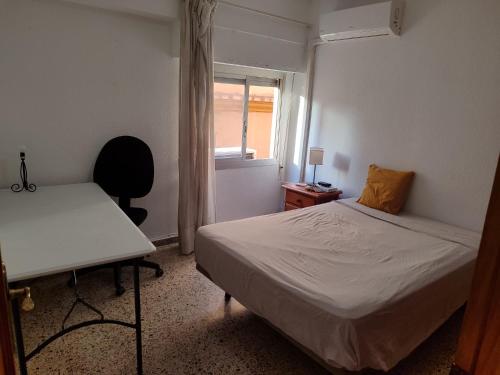 Un dormitorio con una cama y un escritorio y una ventana. en Vivienda Turística Argollones 2022, en Almería