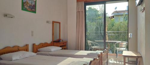 1 dormitorio con 2 camas y balcón con mesa en Kapandriti Rooms, en Skala
