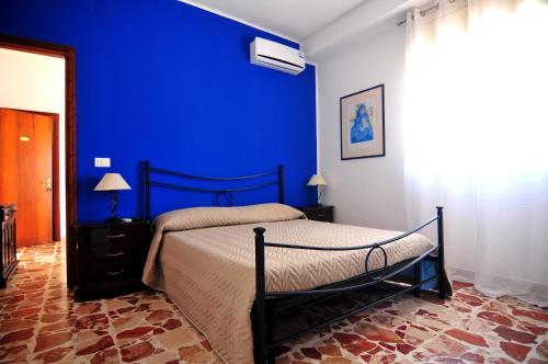 a bedroom with a bed with a blue wall at St. Lucia Suites & Apartments in Syracuse