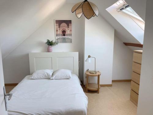 une chambre avec un lit blanc dans un grenier dans l'établissement Grande maison de ville, 2 chambres, à Orléans