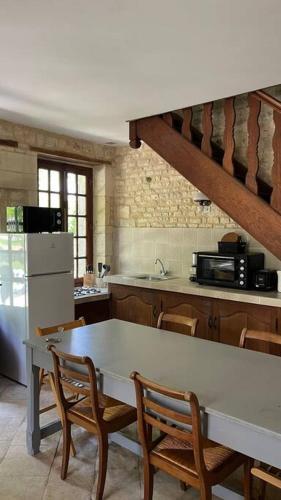 une cuisine avec une table, des chaises et un réfrigérateur dans l'établissement Maison de campagne entre Caen et la mer, à Loucelles