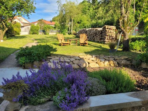 a garden with two wooden chairs and purple flowers at Maison Lombardi - Gite 6 Personnes 4 étoiles in Dun-sur-Meuse