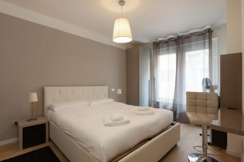 a bedroom with a white bed with a chair and a window at Elegante rifugio Shakespeare con parcheggio a Trieste in Trieste