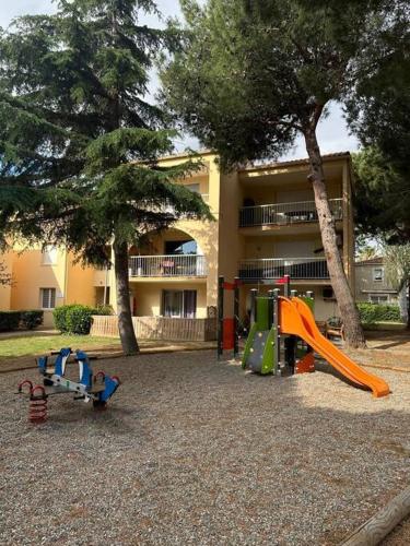 une aire de jeux devant un bâtiment avec un toboggan dans l'établissement Joli T2 au coeur de la résidence Europa à Canet, à Canet