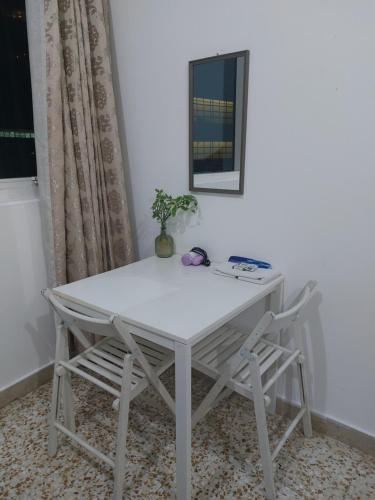 einen weißen Tisch mit 2 Stühlen und einem Spiegel in der Unterkunft Furnished bedroom near Abu Dhabi Corniche in Abu Dhabi