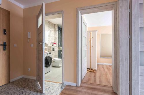 a hallway with a door open to a bathroom with a washer at Nowy apartament - Bulwary nad Sołą - 52m2 in Oświęcim