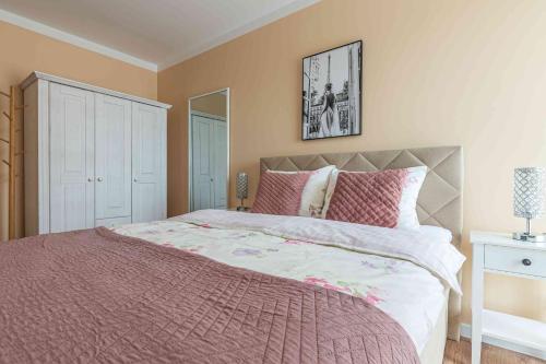 a bedroom with a large bed with pink sheets at Nowy apartament - Bulwary nad Sołą - 52m2 in Oświęcim