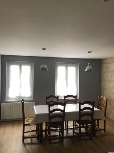 une salle à manger avec une table et des chaises et deux fenêtres dans l'établissement Maison en centre ville de Langeais, à Langeais