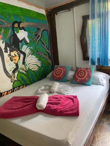 een bed met een vlinderdas erop met een schilderij bij Eco Hostal La Perla Tayrona in El Zaino