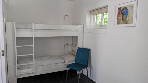 a room with bunk beds with a blue chair at Tversted Strandpark in Bindslev