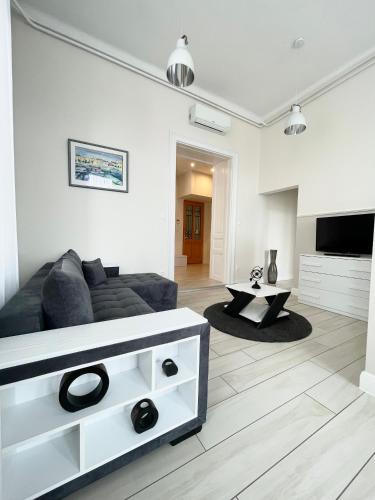 a white living room with a couch and a tv at Trigon Palace in Budapest