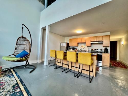a kitchen with yellow chairs and a swing at Swanky Loft Near Kings Island, Brewery, Bike Trail in Maineville