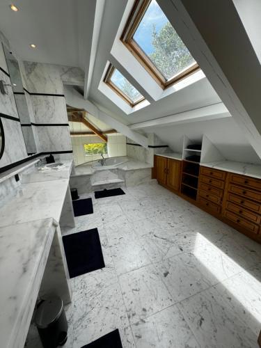 une grande salle de bain avec une lucarne au plafond dans l'établissement Villa de Luxe vue sur Paris, à Chambourcy