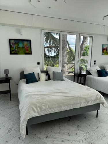 - une chambre blanche avec 2 lits et 2 fenêtres dans l'établissement Villa de Luxe vue sur Paris, à Chambourcy