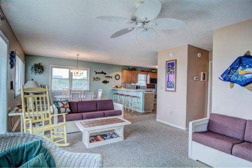 a living room with two purple couches and a kitchen at Back A Bit in Surf City