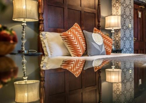a bed with orange and white pillows on it at Broadoaks Boutique Country House in Windermere