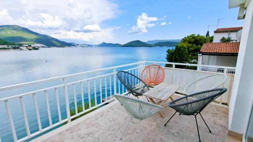 two chairs and a table on a balcony overlooking the water at Apartman Bebic in Klek
