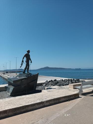 a statue of a man standing on a ledge near the water at Seaview studio in Neapolis