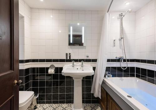 a bathroom with a sink and a bath tub at Broadoaks Boutique Country House in Windermere